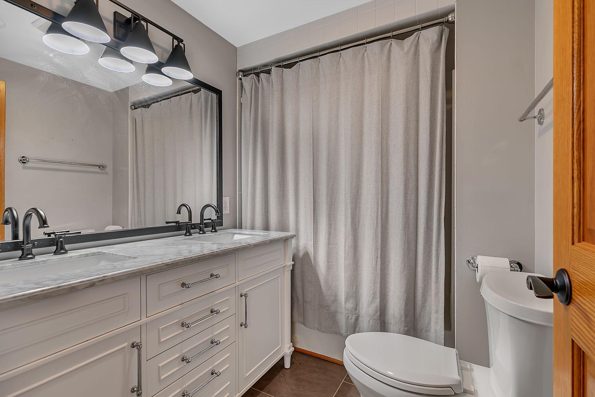 Lower level full bath featuring dual sinks.