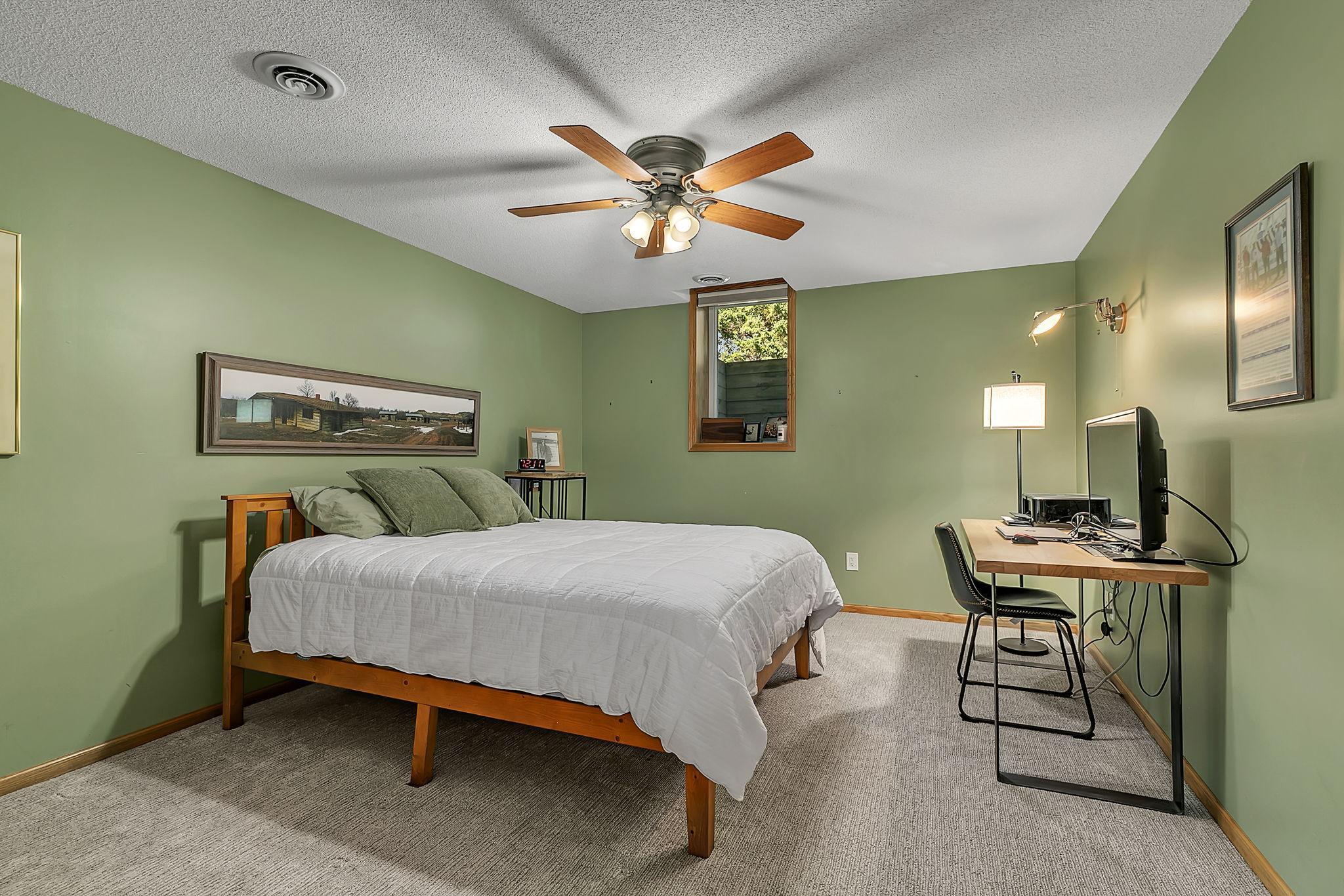 Second lower level bedroom featuring updated carpet, ceiling fan and spacious closet.