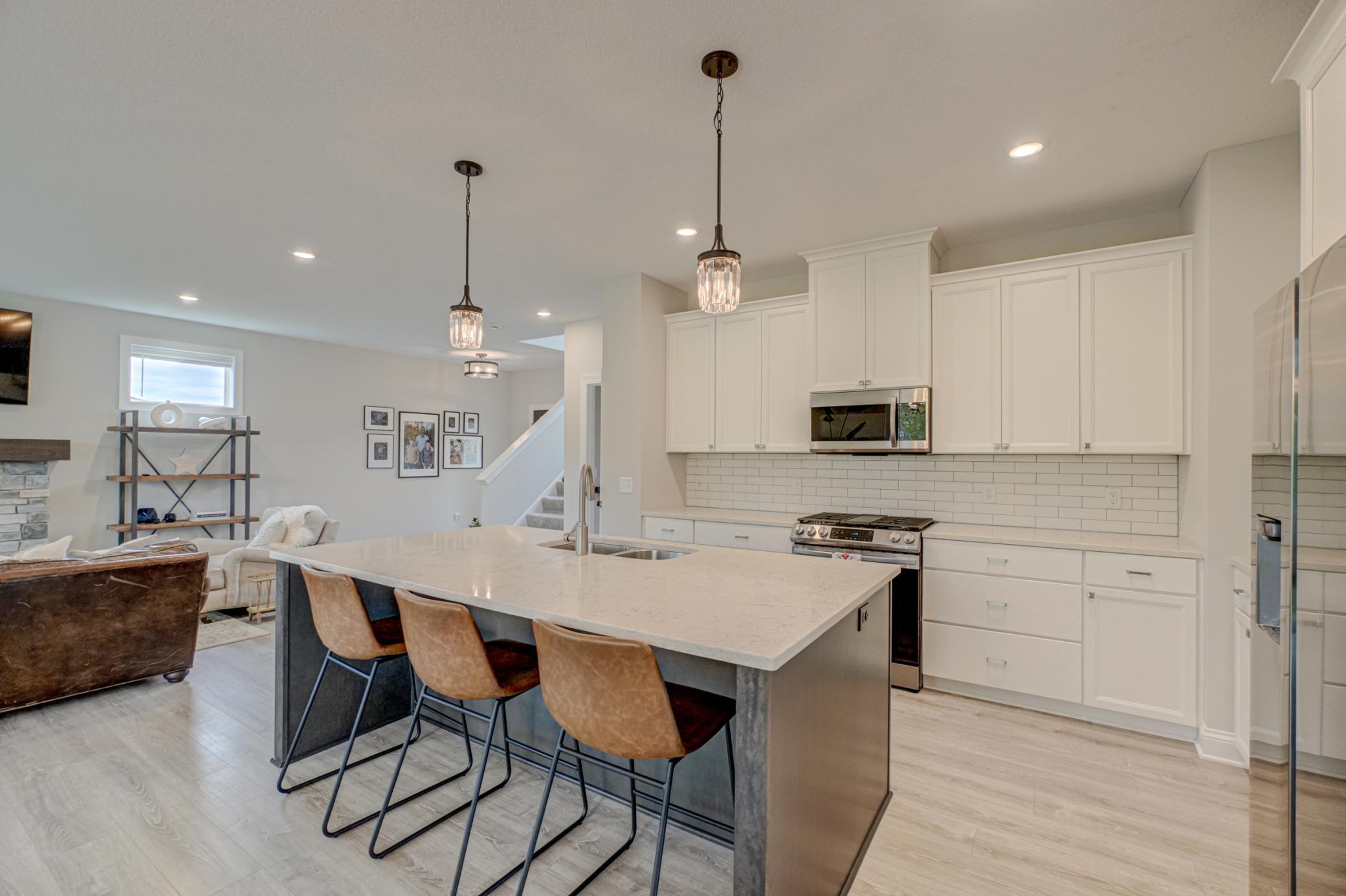 A sleek, stylish kitchen offers stainless steel appliances, a clean backsplash, and an oversized center island that connects effortlessly to the main living spaces, making it ideal for both daily living and hosting.