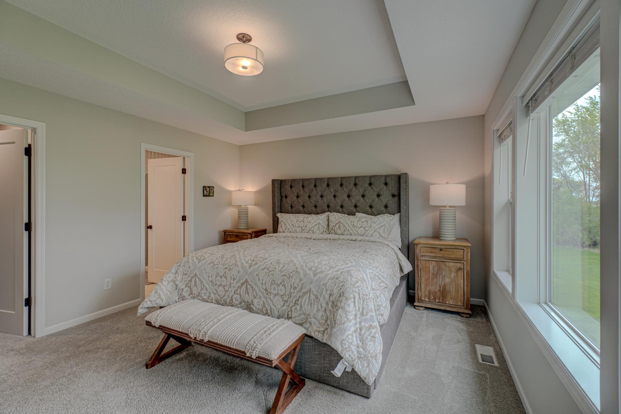Private primary suite featuring a stepped tray ceiling, a walk-in closet, and an ensuite bath featuring double vanities.
