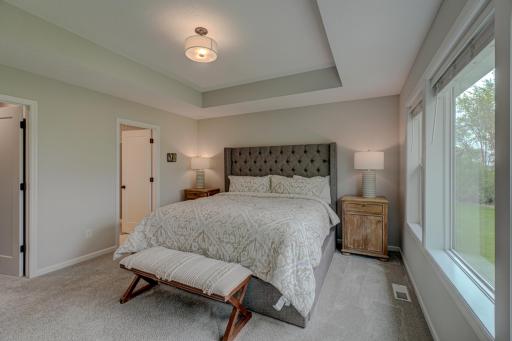Private primary suite featuring a stepped tray ceiling, a walk-in closet, and an ensuite bath featuring double vanities.