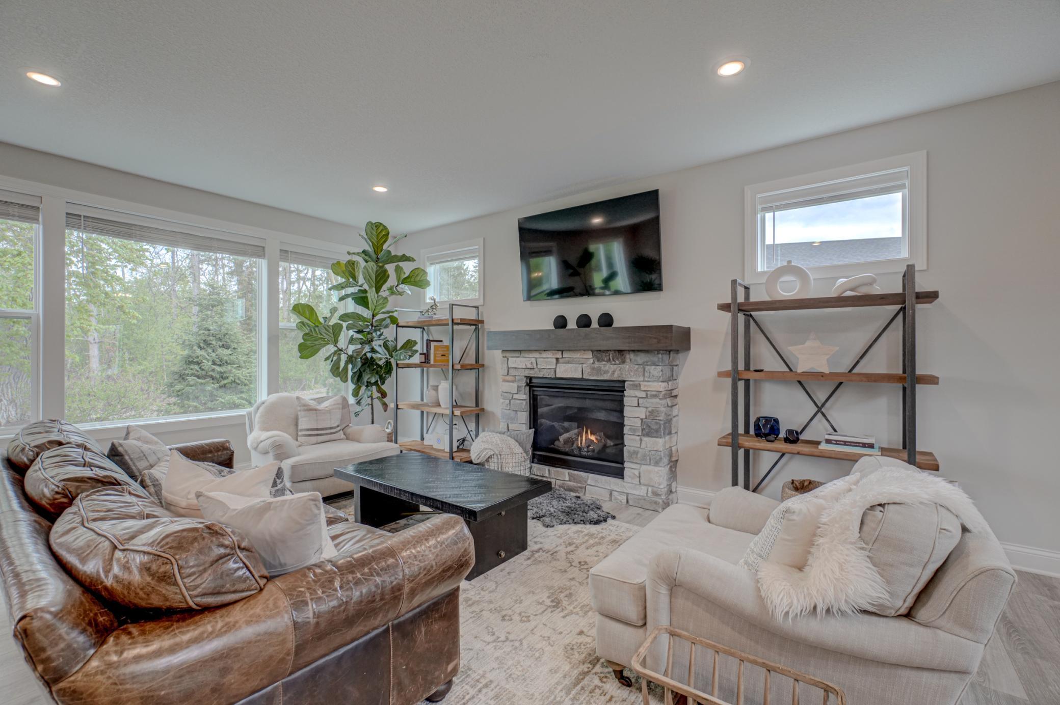 The inviting living room is anchored by a beautiful stone fireplace, while large windows bring in abundant natural light and frame peaceful wooded views.