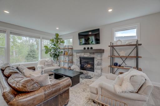 The inviting living room is anchored by a beautiful stone fireplace, while large windows bring in abundant natural light and frame peaceful wooded views.