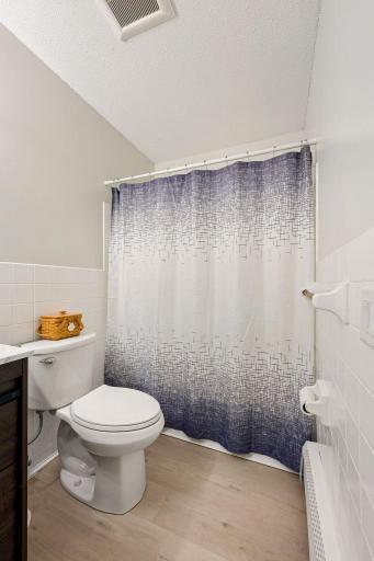 Freshened full bathroom with vinyl plank flooring and neutral paint.