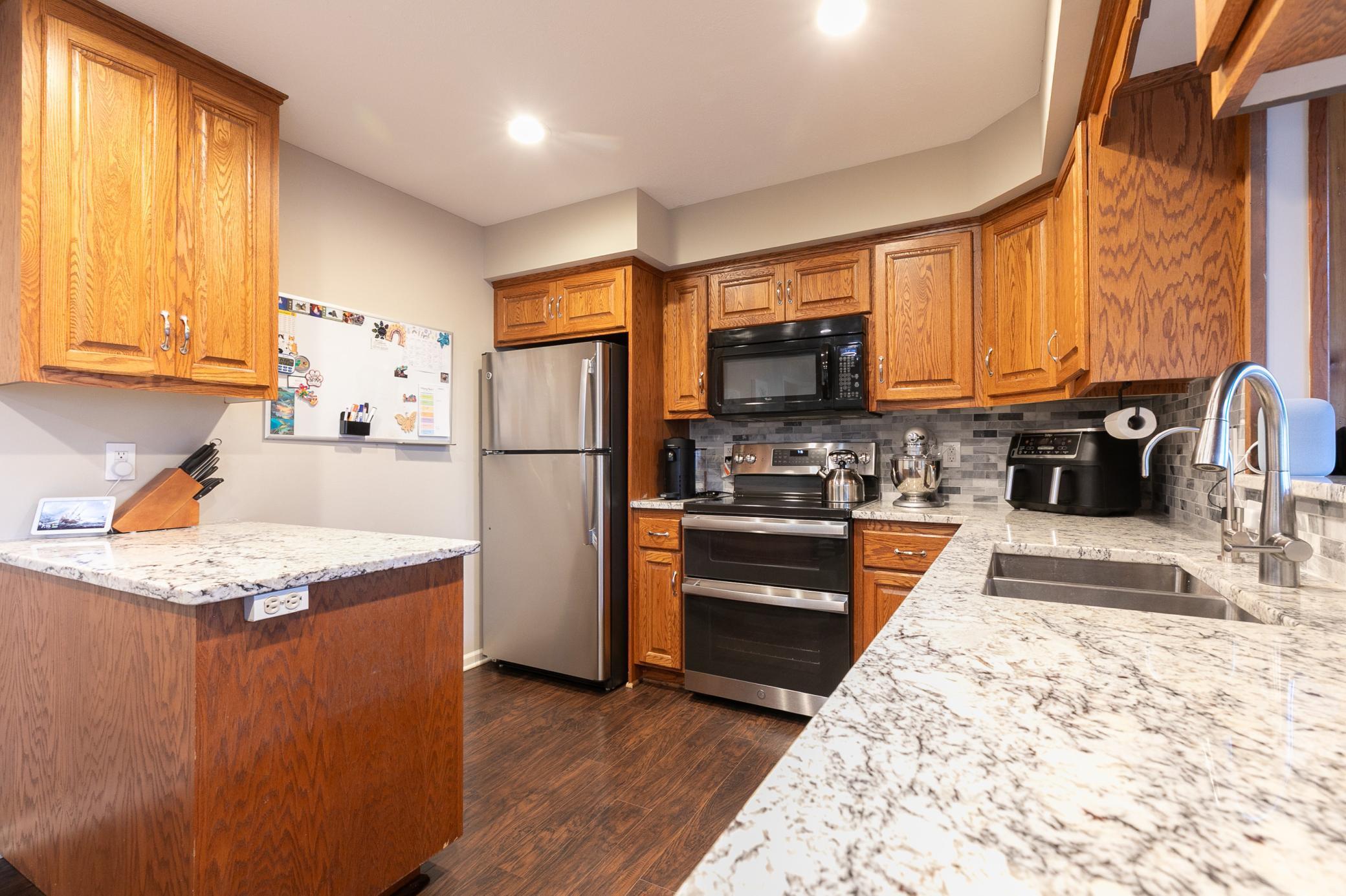 This kitchen features granite countertops (installed in 2021), beautifully complemented by newer appliances - Dishwasher (2024), Refrigerator (2020), Electric Range (2021)