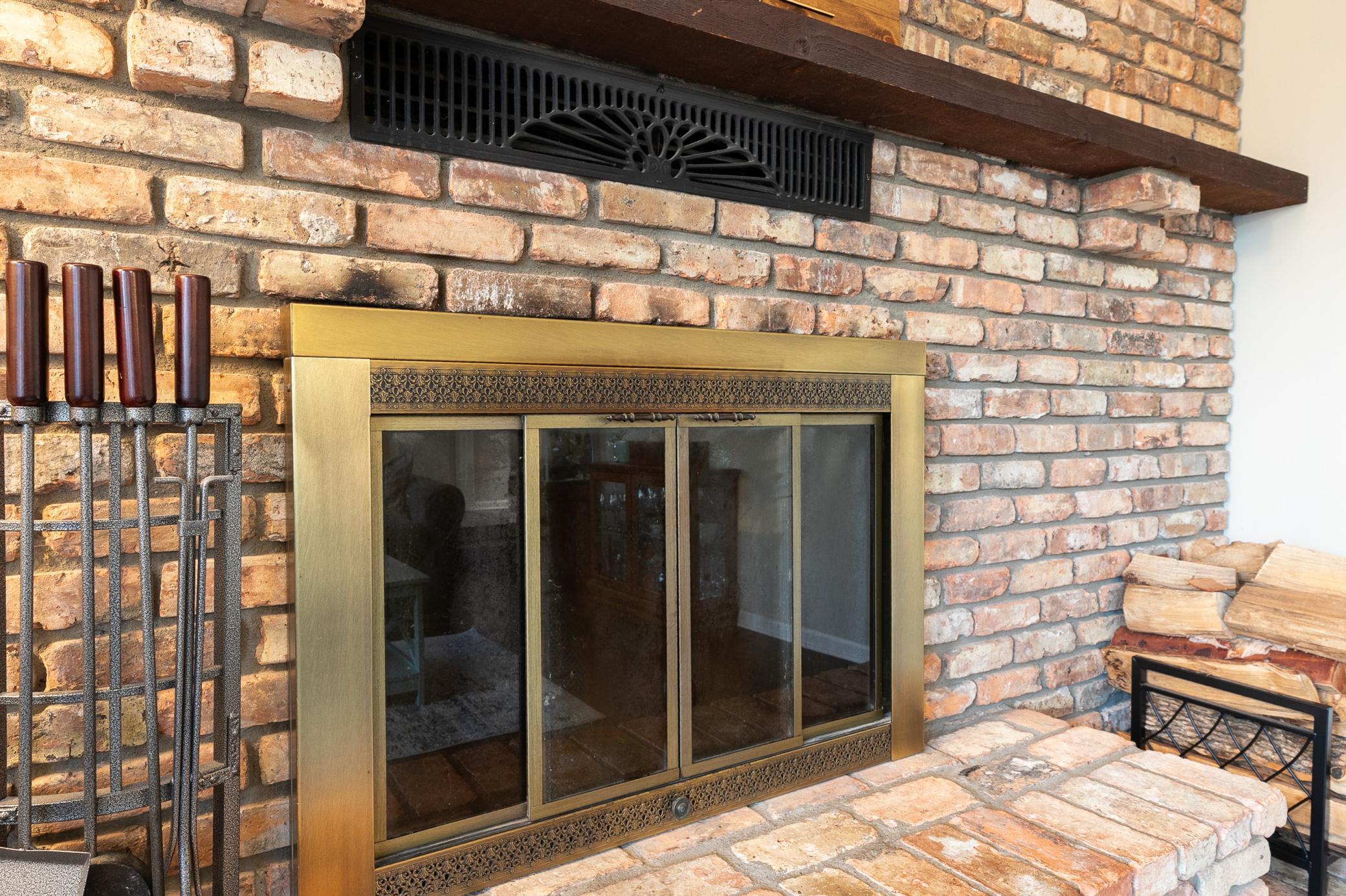 The wood burning fireplace with a brick surround creating a warm and cozy setting