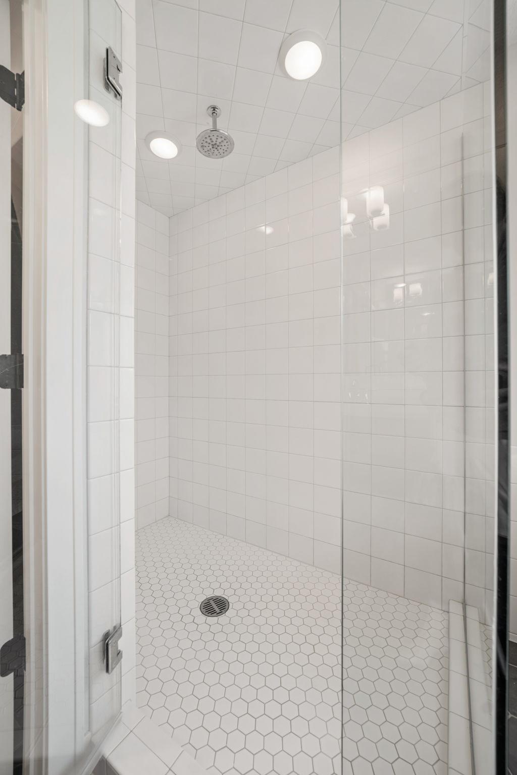 Custom tile shower offers a rain shower head and partial glass enclosure