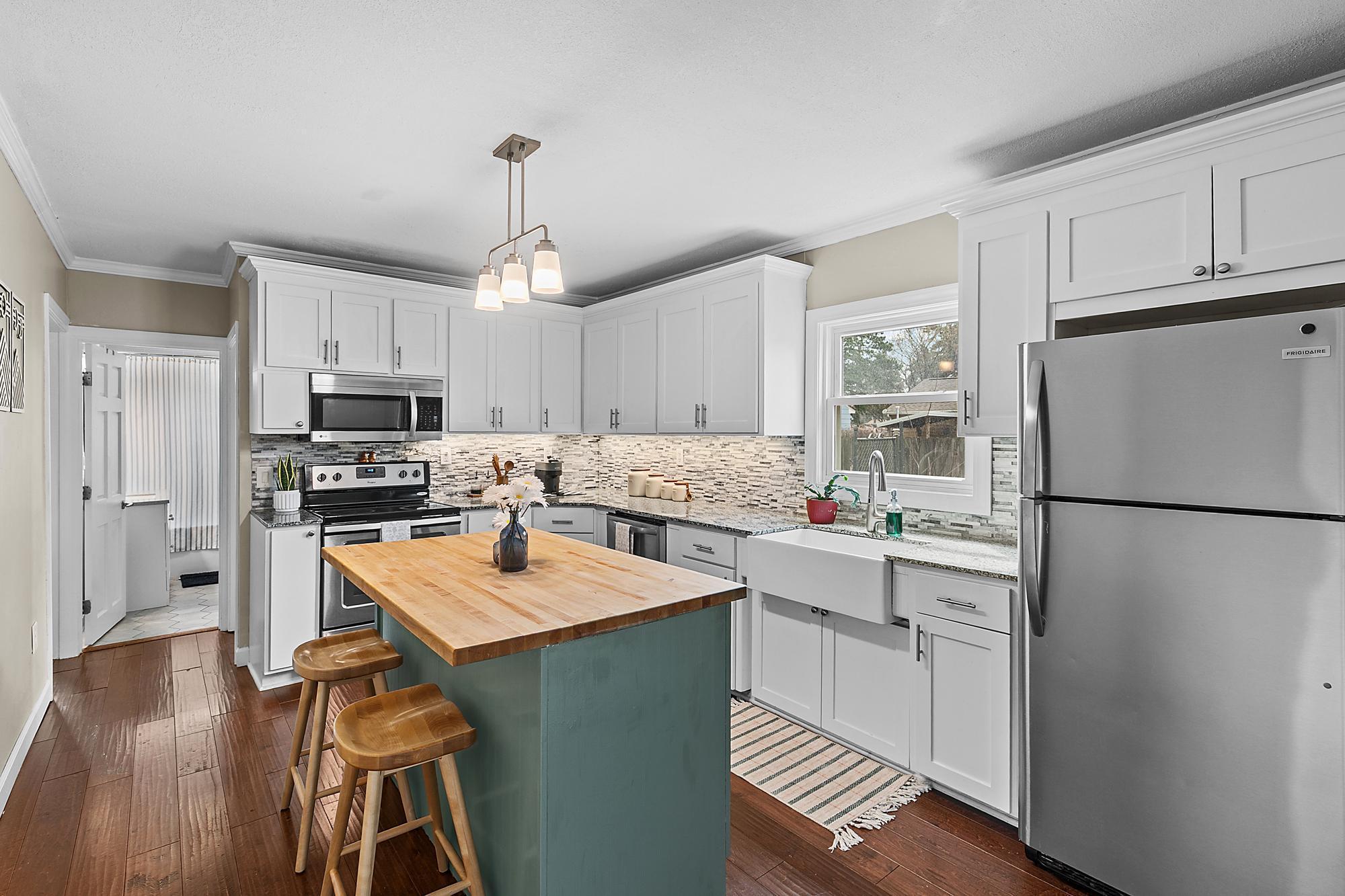 Updated kitchen with gorgeous backsplash, stainless appliances and white cabinets.