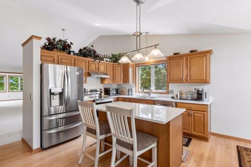 The bright and functional kitchen features updated quartz countertops, stainless steel appliances, abundant cabinetry, and a center island with seating.