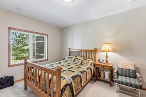 This spacious lower-level bedroom provides a quiet retreat with large windows that bring in natural light and showcase the surrounding greenery.