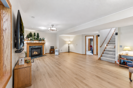 The expansive walkout lower level offers a versatile gathering space with durable flooring, large windows, and a cozy gas fireplace.
