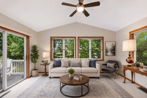 Escape to the sun-filled four-season room, where vaulted ceilings, expansive windows, and serene treetop views create a peaceful retreat. (digitally staged)