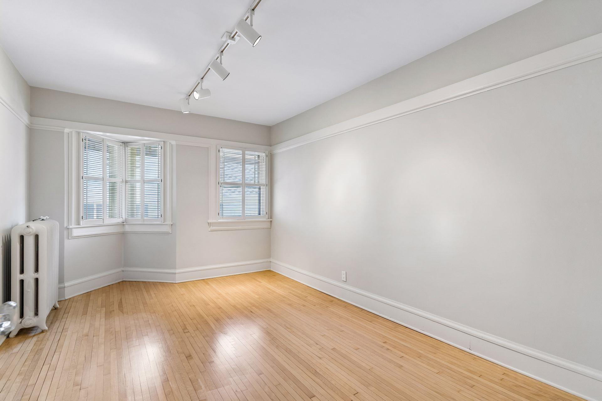 Another spacious bedroom showcasing unique character and beautiful hardwood floors.