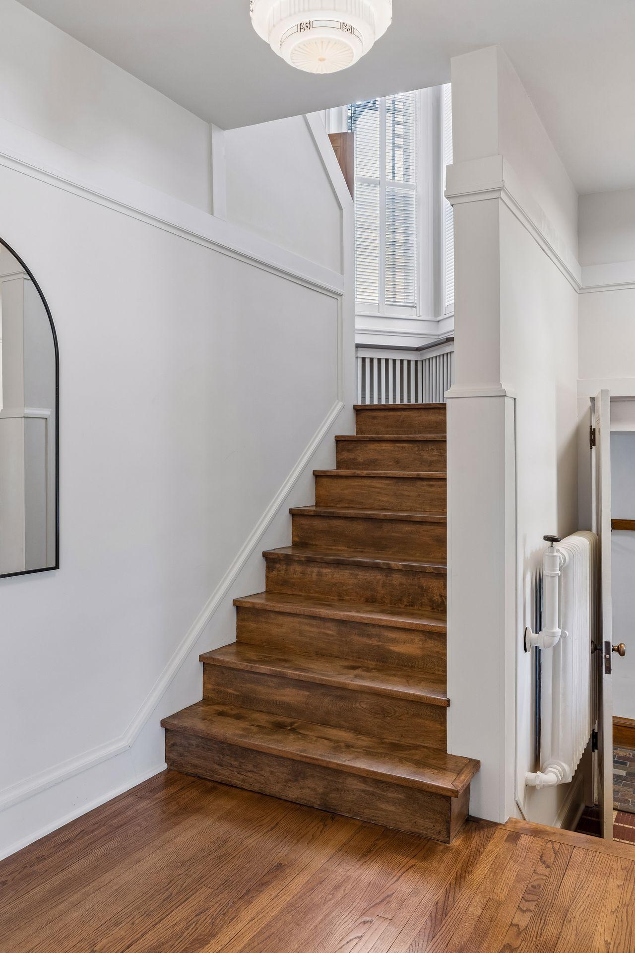 A stunning wood staircase and rich hardwood floors create a warm and timeless first impression.