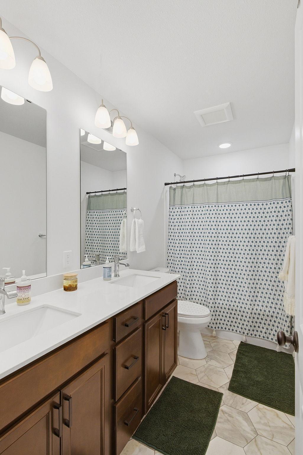 The upper level features a full bathroom with dual sinks and an abundance of room