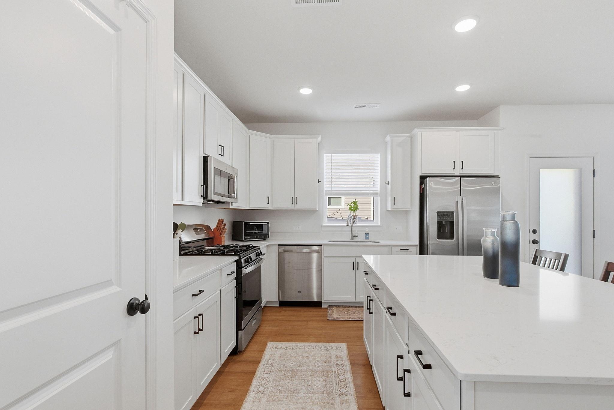 This amazing kitchen showcases stainless steel appliances covered under the home warranty and an endless center island that serves as the heart of the home, perfect for gathering and entertaining.
