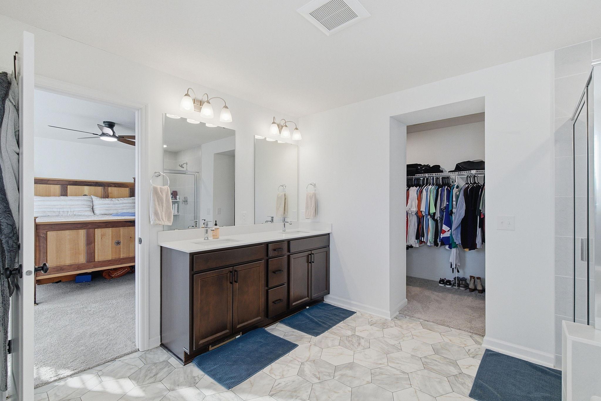 The owner’s bathroom offers dual sinks, a private toilet space, separate shower and soaking tub, and an oversized walk-in closet.