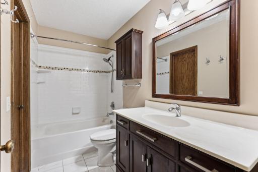 Crisp white tile lines the shower and tub, paired with a dark vanity, a framed mirror, and chrome fixtures, creating a clean, timeless main bath.