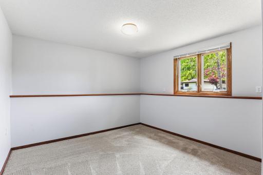 Carpet, light walls, and a side-yard window give this lower-level bedroom a calm, ready-to-style canvas for guests, or quiet study time.
