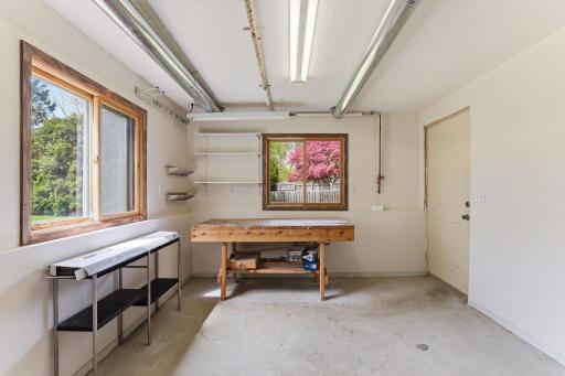 Inside a semi-finished workshop space, painted walls, dedicated shop lighting, and a workbench keep tools, projects, and seasonal gear neatly in their place.