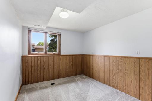 Wood wainscoting adds character to this lower-level bedroom, lifted by light walls above and a window framing the yard.