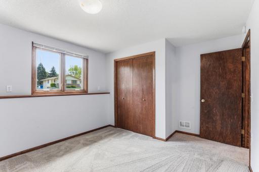 Fresh carpet, a deep closet, and a wide window make this lower-level bedroom ready for guests or a long workday at home.