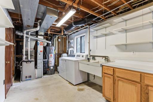 Behind the laundry, the furnace, water heater, and main mechanical equipment line one wall, with a window and ducting kept tidy overhead.