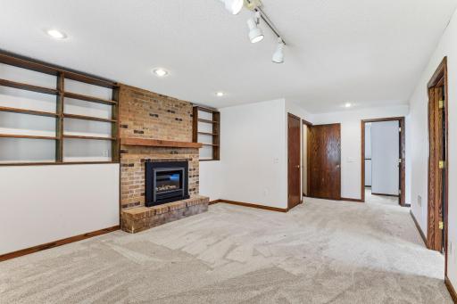 Built-in shelving wraps both sides of the brick fireplace, with the bedroom and additional rooms opening just beyond.