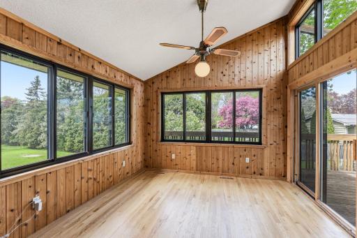 Windows wrap two full walls of the sunroom, opening views to mature trees, spring blooms, and the backyard all year long.
