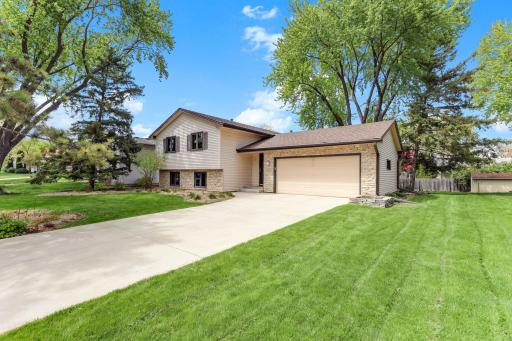 Stone accents wrap the front and garage base, fresh siding, and the concrete drive sweeps cleanly to the two-car attached garage.