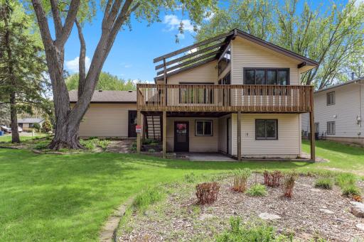 Stepping back, the home's signature back elevation comes into view: deck above, sunroom centered, and a sheltered lower-level entry below.
