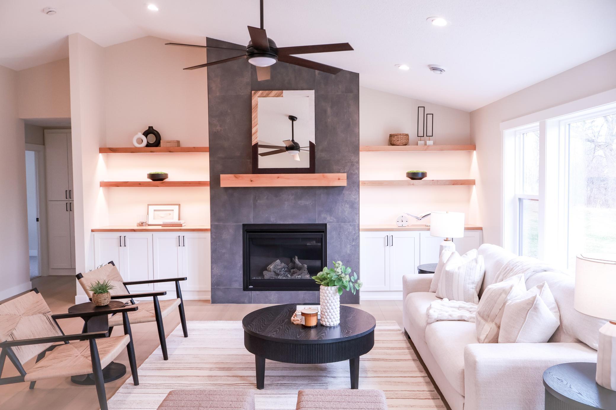 The focal point of this living area is a cozy fireplace and stylish floating shelves.