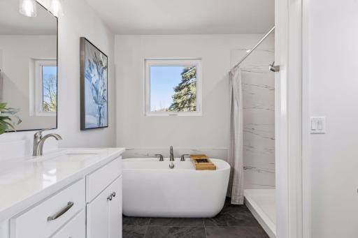 Primary bathroom with soaking tub, separate shower, and tile finishes. Bright space with window for natural light.