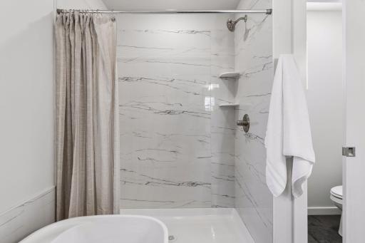 Stylish walk-in shower with large-format tile surround and built-in shelving for convenience. Clean, modern finishes create a spa-like feel in this full bathroom.