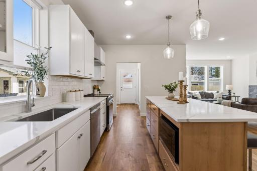 Beautifully designed kitchen featuring a farmhouse sink, quartz countertops, and abundant cabinetry for excellent storage. Microwave conveniently built into the island, with easy flow to the mudroom and backyard - ideal for everyday living.