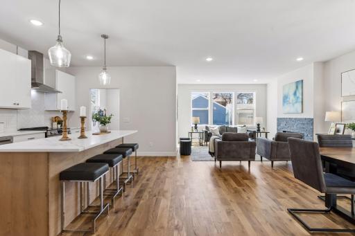 Open-concept main level showcasing spacious design with seamless flow between living and dining areas. Enhanced by modern, energy-efficient lighting, hardwood floors, and abundant natural light -ideal for everyday living and entertaining.