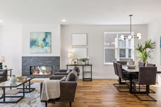 Living room highlighted by a sleek electric fireplace with modern surround, creating a stylish focal point. Large windows and hardwood floors complete this bright and comfortable space.