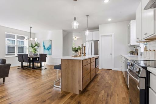 Spacious kitchen featuring a large center island, quartz countertops, and an electric range with modern hood. Generous walk-in pantry provides excellent storage. Open layout flows seamlessly into the dining area.
