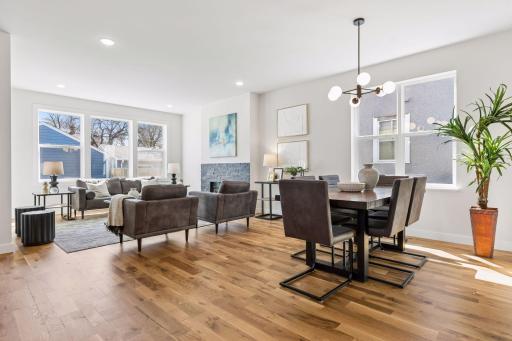 Bright dining area with large windows and modern lighting fixture, perfectly positioned between kitchen and living room for easy flow.