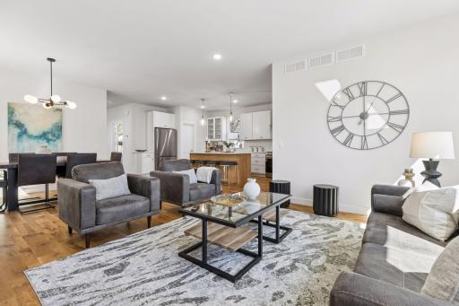 Spacious living room with large windows and abundant natural light, flowing seamlessly into the dining area and kitchen. Open-concept design with hardwood floors, ideal for everyday living and entertaining.