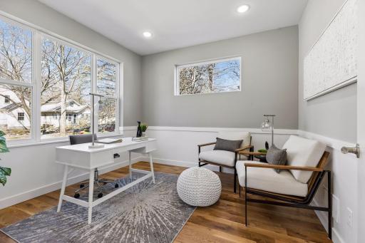 Main level office with large windows, hardwood floors, and flexible use as a guest bedroom or workspace. Bright and comfortable with modern finishes.
