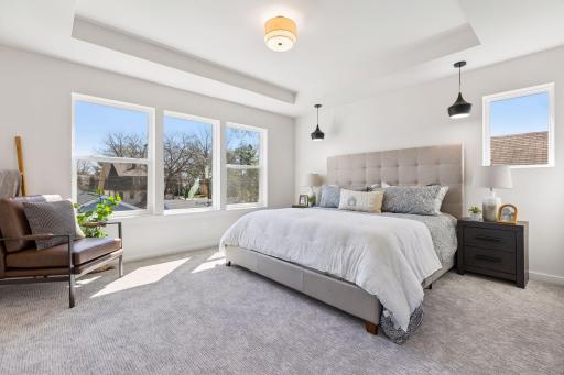 Spacious primary bedroom overlooking the backyard, filled with natural light. Features a tray ceiling and comfortable carpeting for a warm, inviting feel, with plenty of space for a sitting area.
