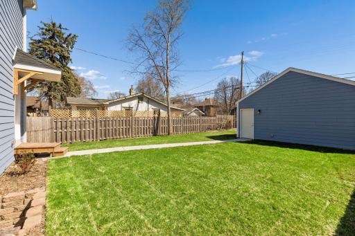 Another view of the partially fenced backyard showcasing open lawn area and space to relax or entertain.
