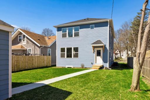Partially fenced backyard with green space and a concrete path leading to the garage - perfect for easy access, outdoor living, play or gardening.
