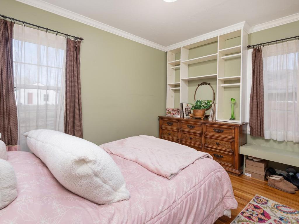 Main level Bedroom has hardwood floor and vintage dresser with shelves above that stay with the home.