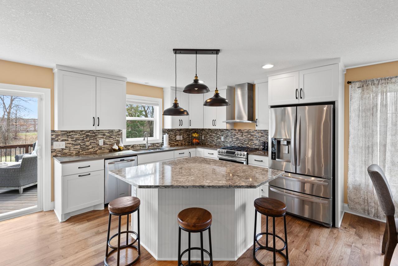 Updated kitchen with Cambria countertops, stainless steel appliances, custom cabinets, and a large center island with seating, open to the deck for easy entertaining.