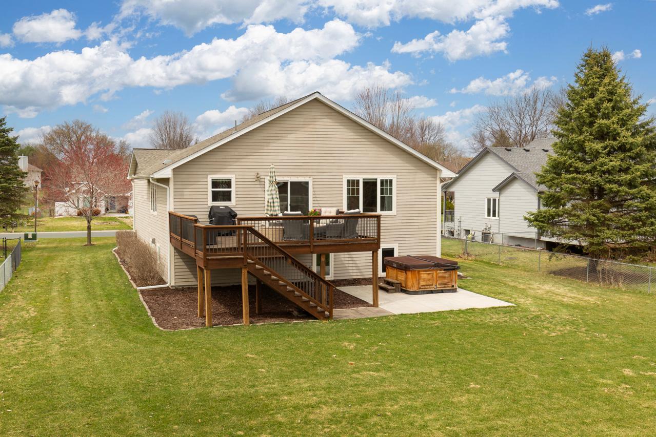 Expansive backyard featuring a large deck, patio area, and hot tub—perfect for outdoor entertaining and relaxation.