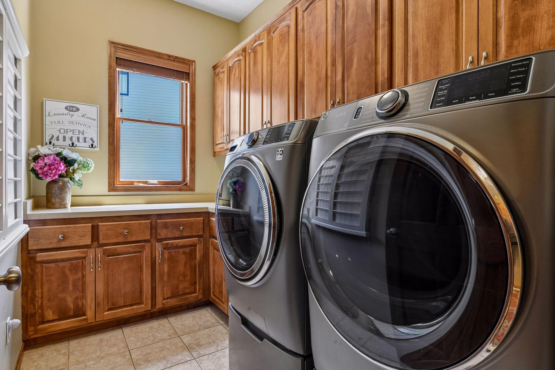 The Laundry Room features a new GE steam washer and dryer with pedestals, extensive cabinetry and a laundry sink.