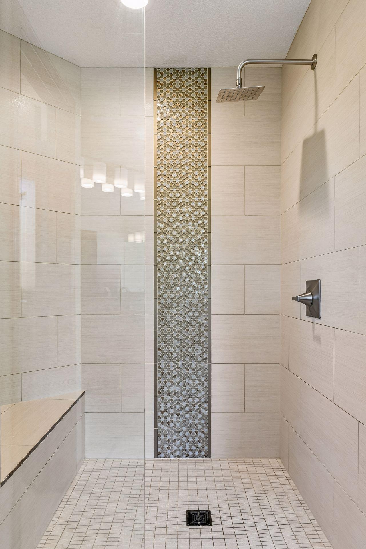 The spacious shower has been updated with new tile, a built-in bench and frameless glass enclosure.