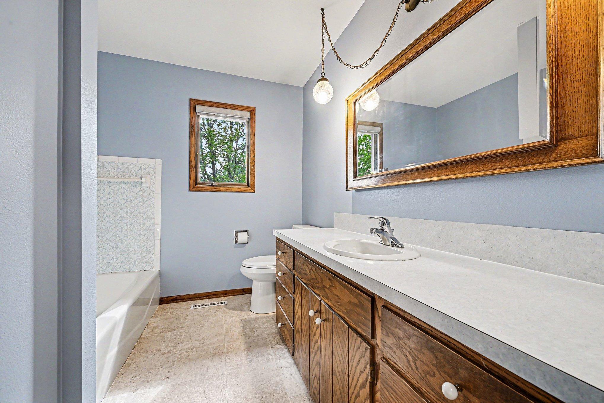 Main-level full bath with long vanity and wood cabinetry
